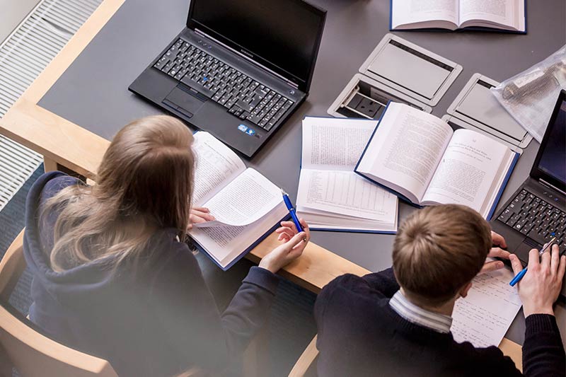 Close up of students studying in McClay Library using laptops