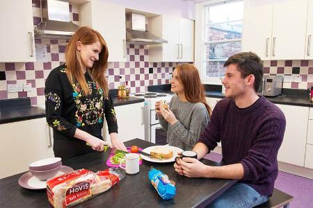 student making lunch and chatting with flatmates in Elm's Village