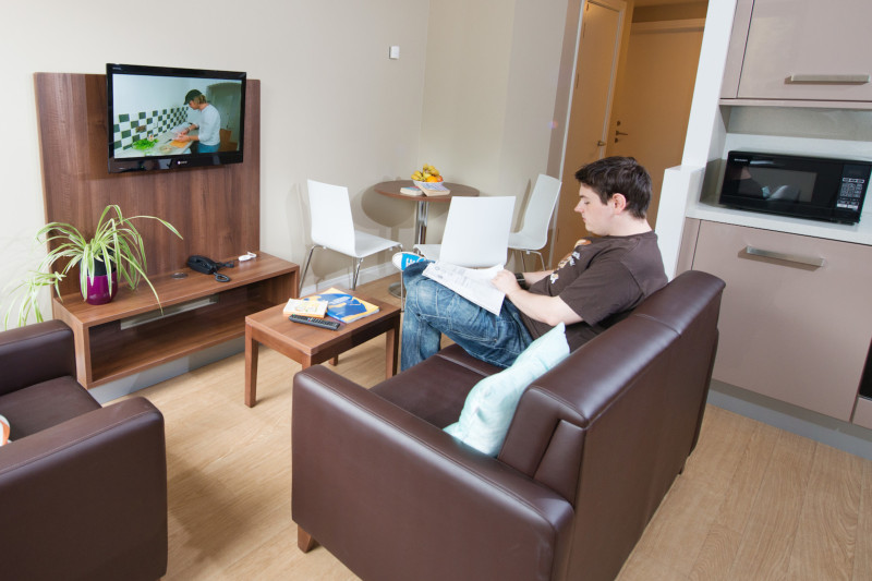 A male student looking at lecture notes in the living room of a Willow Walk student accommodation flat