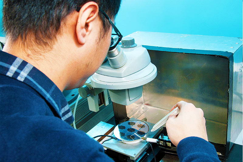 Student examining a microchip through a magnifying lens