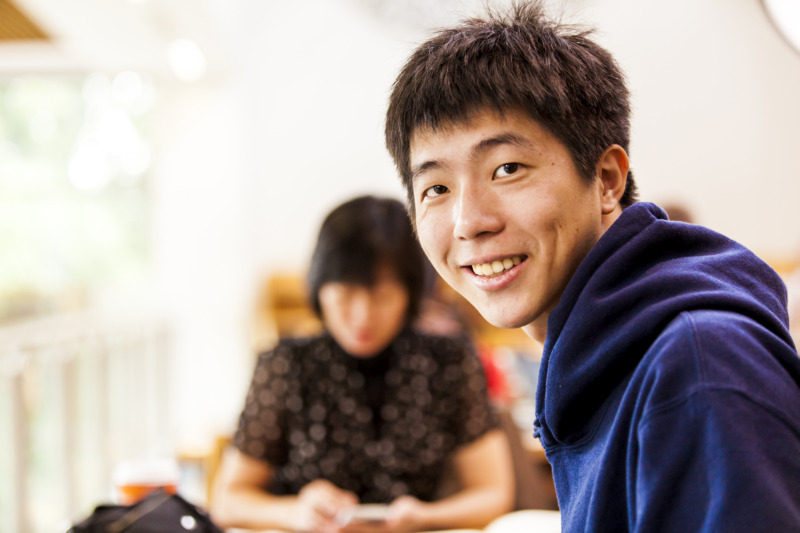 male Asian student wearing blue hooded jumper