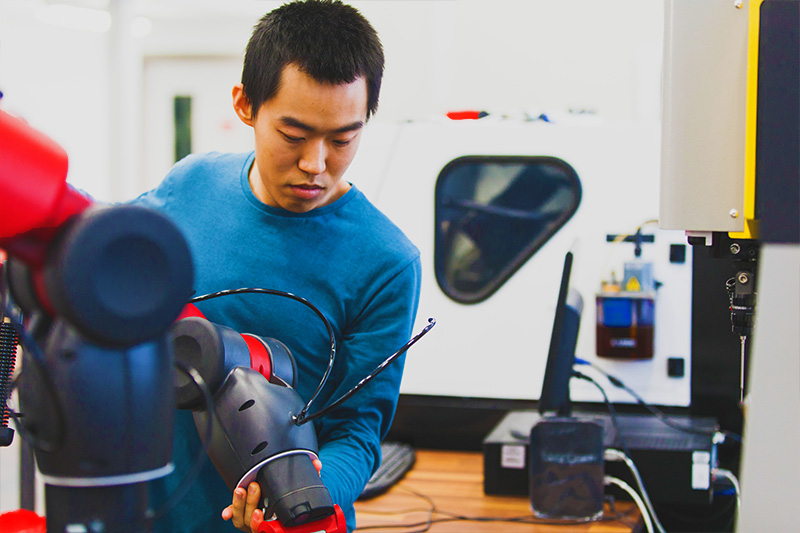 mechanical engineering student using manouevering a robotic arm