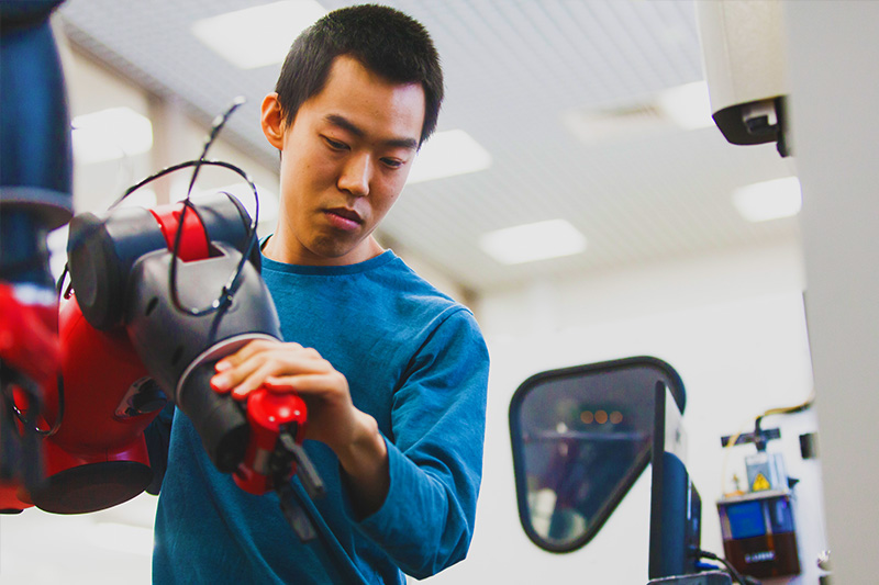 mechanical engineering student using manouevering a robotic arm