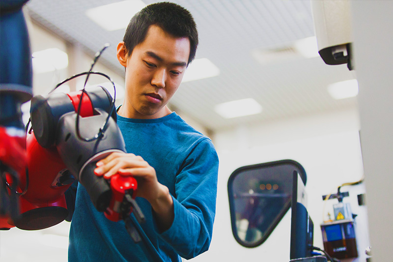 mechanical engineering student using manouevering a robotic arm
