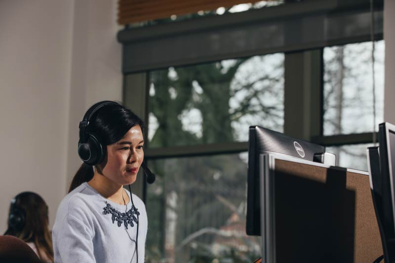 international student using a computer with headphones in the QUB language centre