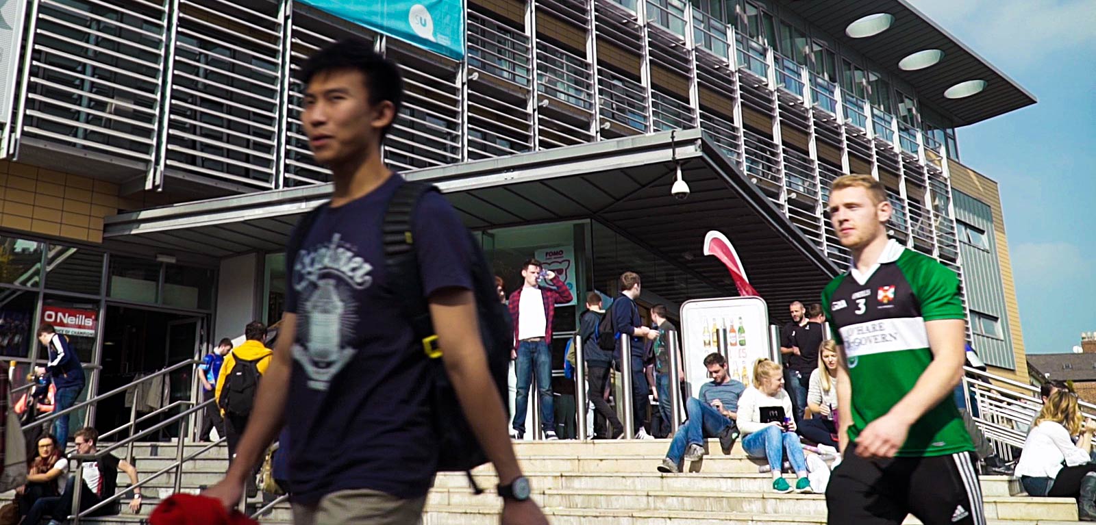 students walking past the exterior of the Queen's University Belfast Students' Union (QUBSU)