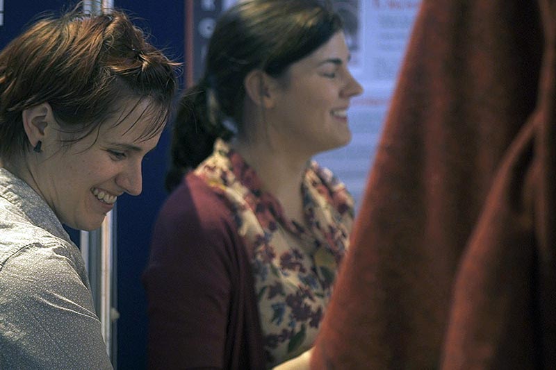 two female students smiling and looking at research posters at a poster competition in the graduate school