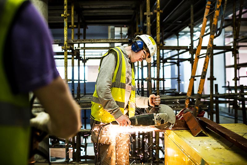 a builder using a circular saw to cut a piece of metal