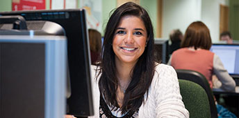 female student behind a computer smiling