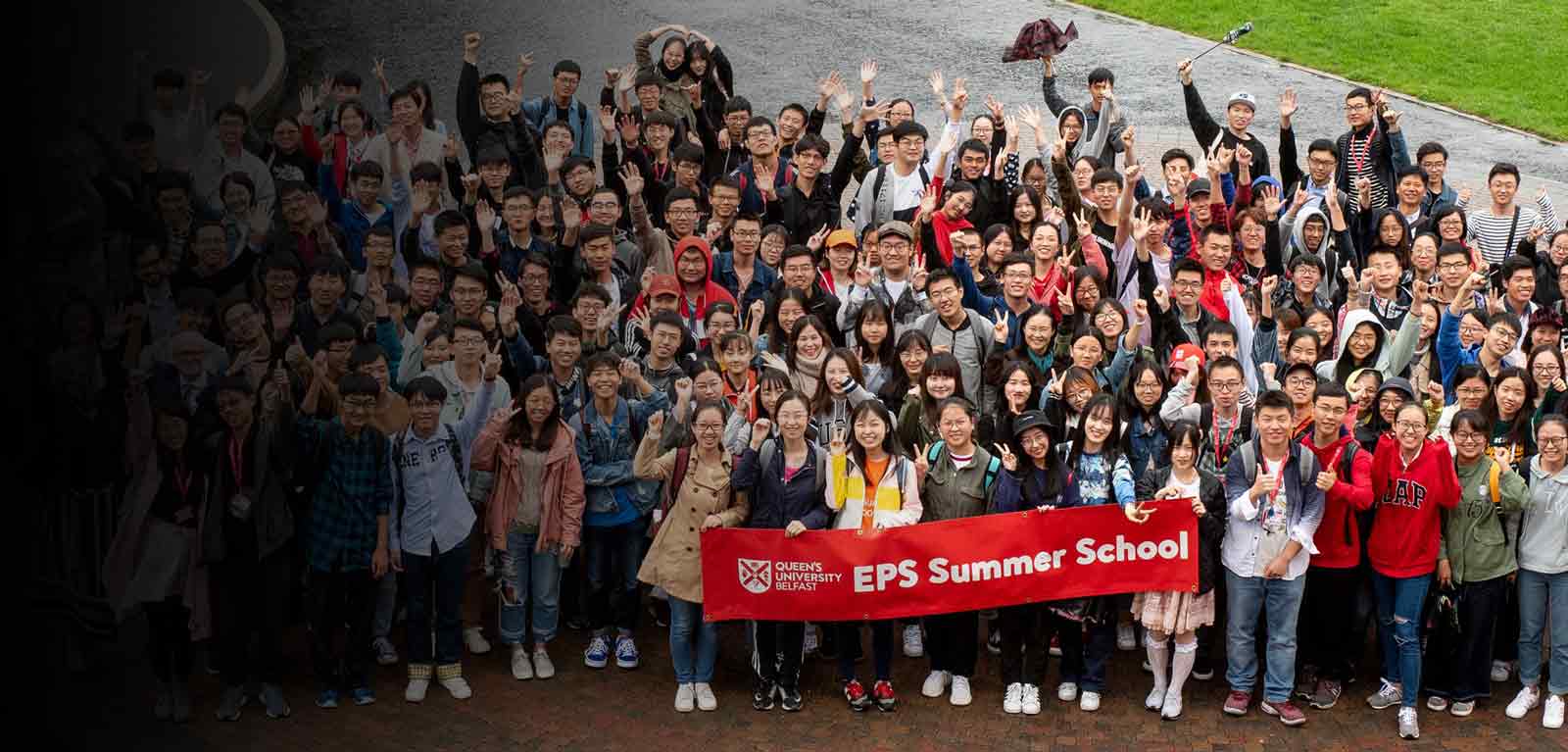 Large group of Summer School students posing with a red banner