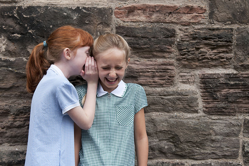 Two schoolgirls whispering
