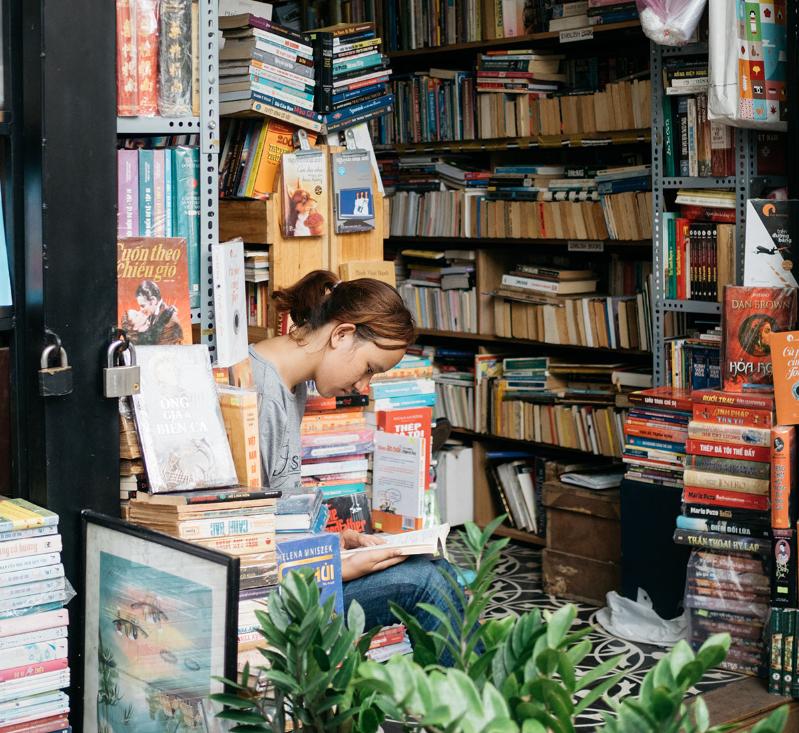 A woman sits in a bookshop reading