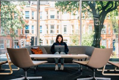 Student sits at a table with Queen's buildings behind her