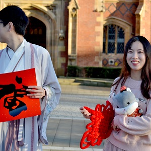 Students from the chinese society smile and hold chinese symbols of good luck