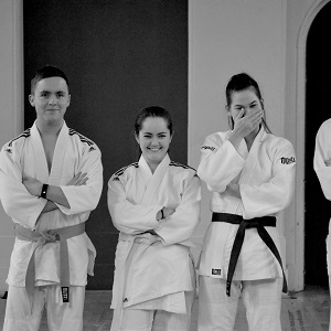 Black and white shot of four judo players, one player has begun to laugh