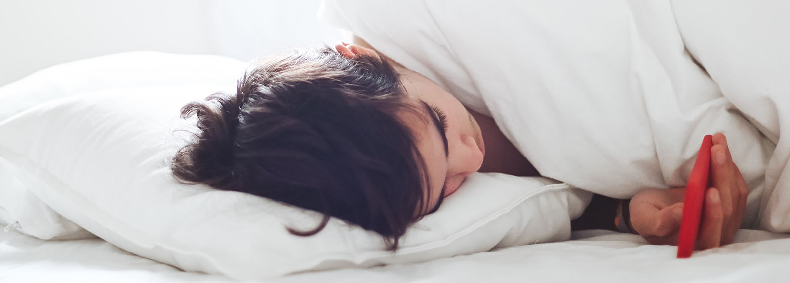 Woman looks at her phone in bed