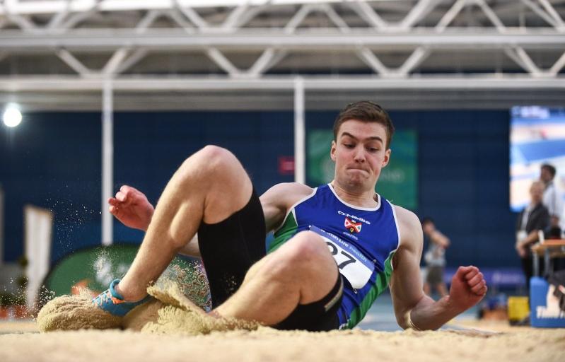 Action shot of an athlete long jumping into the sand