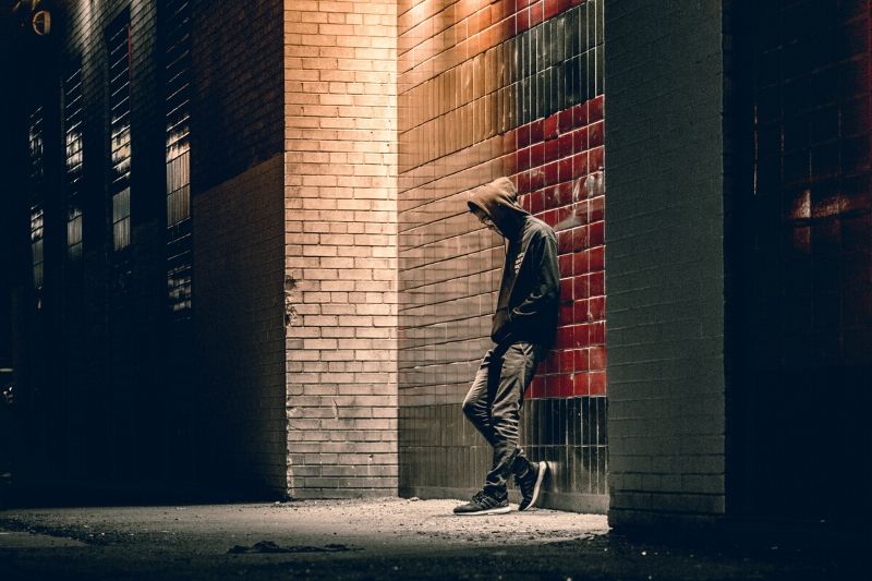 Youth idles by a building at night