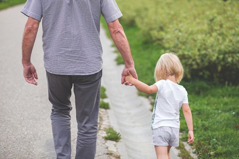 Man holding hands with child and walking along