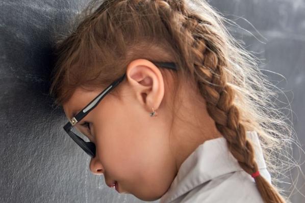 Child with her head against a blackboard 