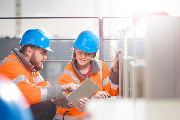 man and woman with hard hats looking at a chart