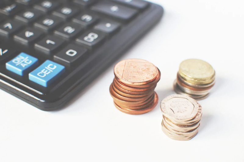 Image shows a calculator and coins