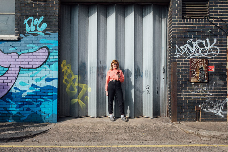 Student on mobile phone in front of grey door
