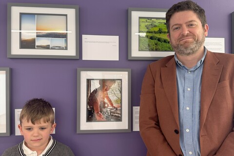 Male student and their son in front of his image submission for AEL photography competition