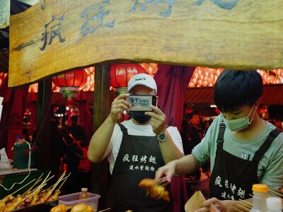 Man at food stall in China taking photo