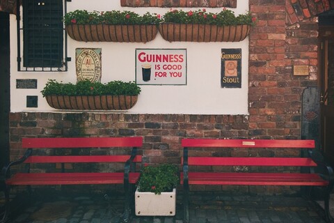 Outside Belfast bar with Guinness sign on wall behind red bench