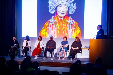people sitting on chairs on a stage during a panel discussion
