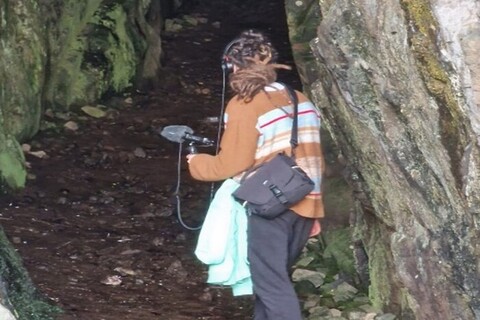 Student recording water sounds in a cave