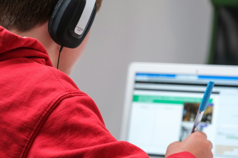 Child working on computer while wearing headphones