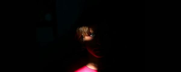 child in a pink top in dark shadows