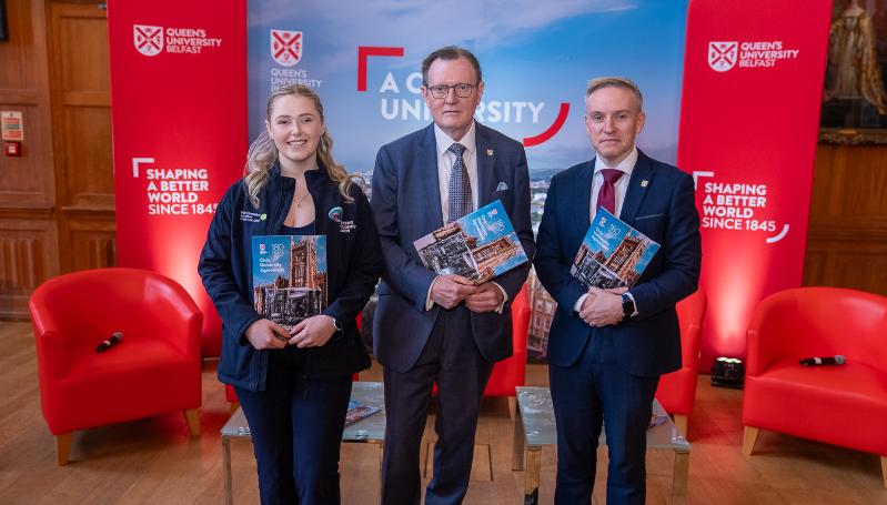 Three people stand with a Civic University Agreement document looking at the camera