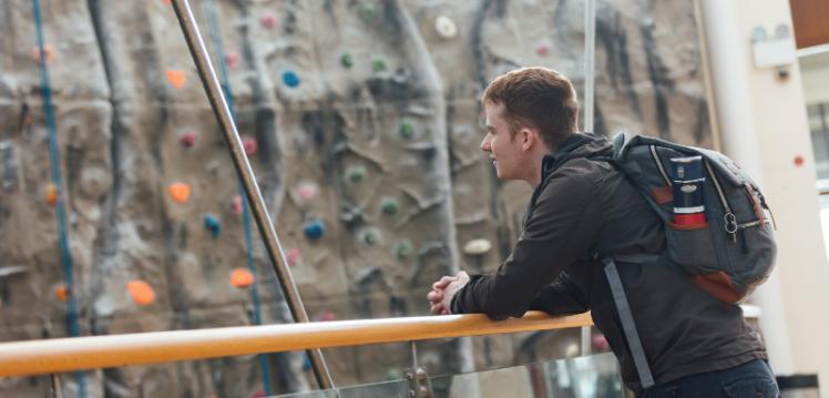 Student in front of climbing wall in the PEC