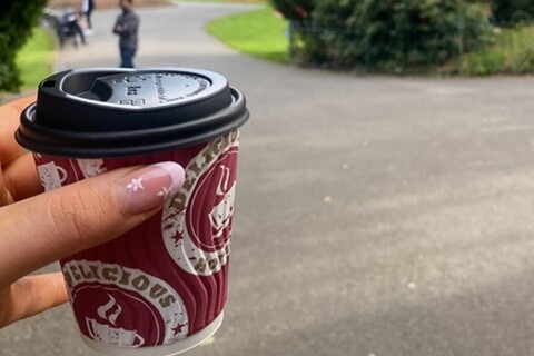 Student holding takeaway coffee cup in Botanic Gardens