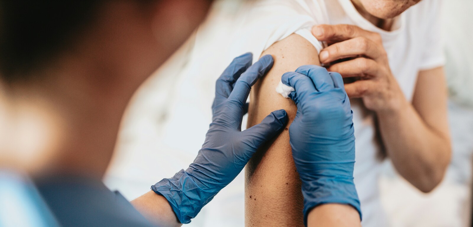 Doctor applying cotton wool to patient's arm