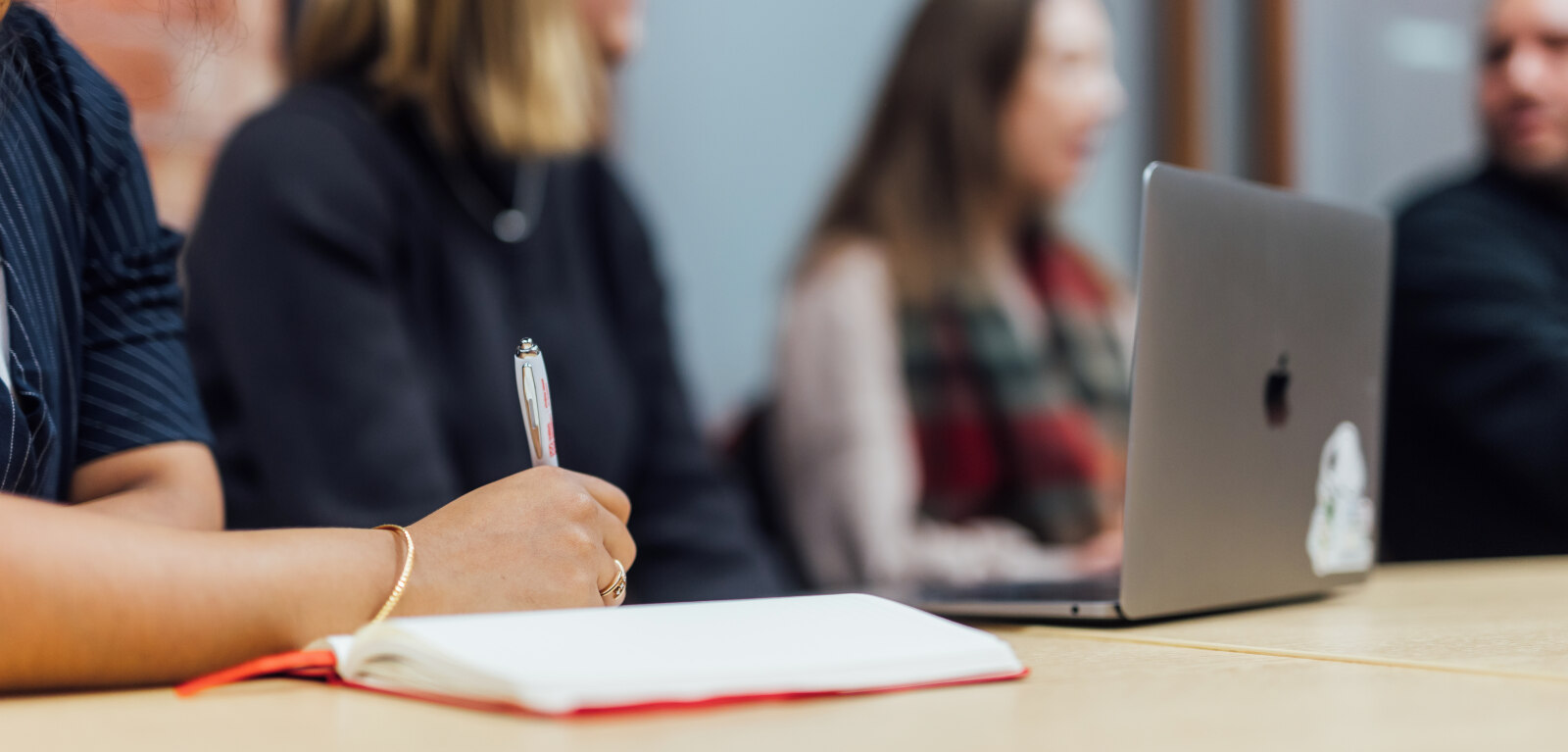 Student writing on notebook in Grad School study room