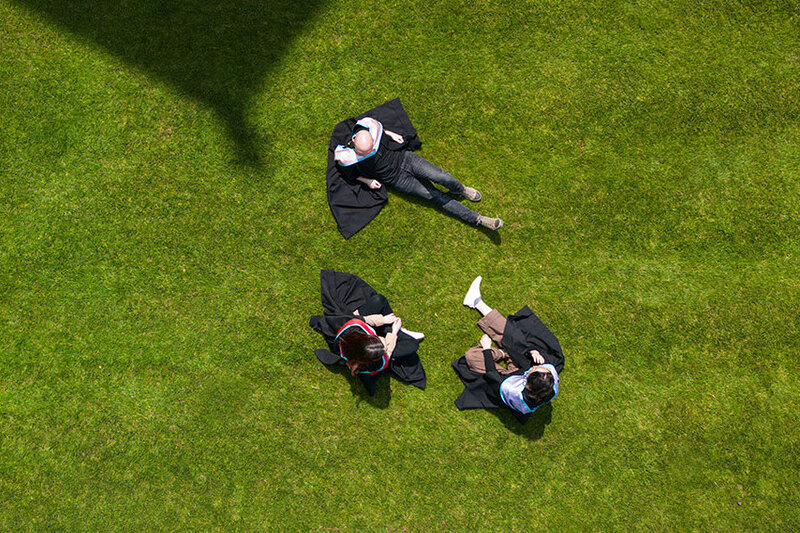 3 grad students sitting on grass