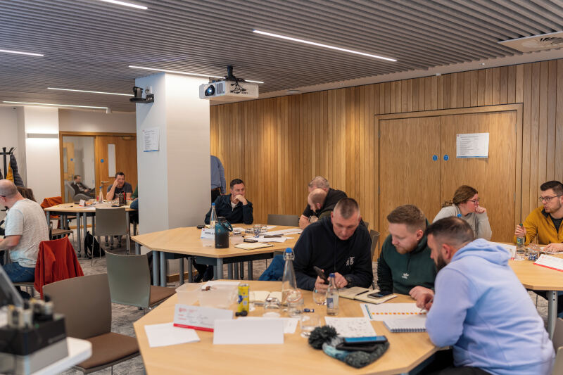 Groups sitting at tables in Queen's Business School