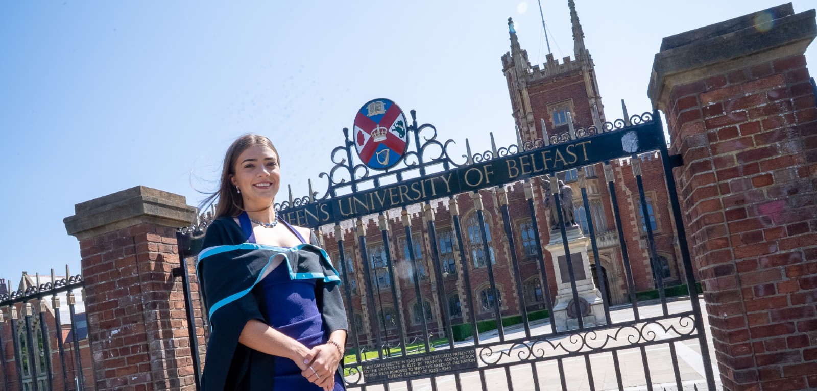 A graduate pictured outside the gates of Queen's University Belfast