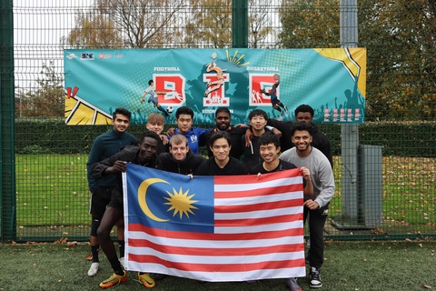 Student Keith in a group of students from a football team holding a Malaysian flag