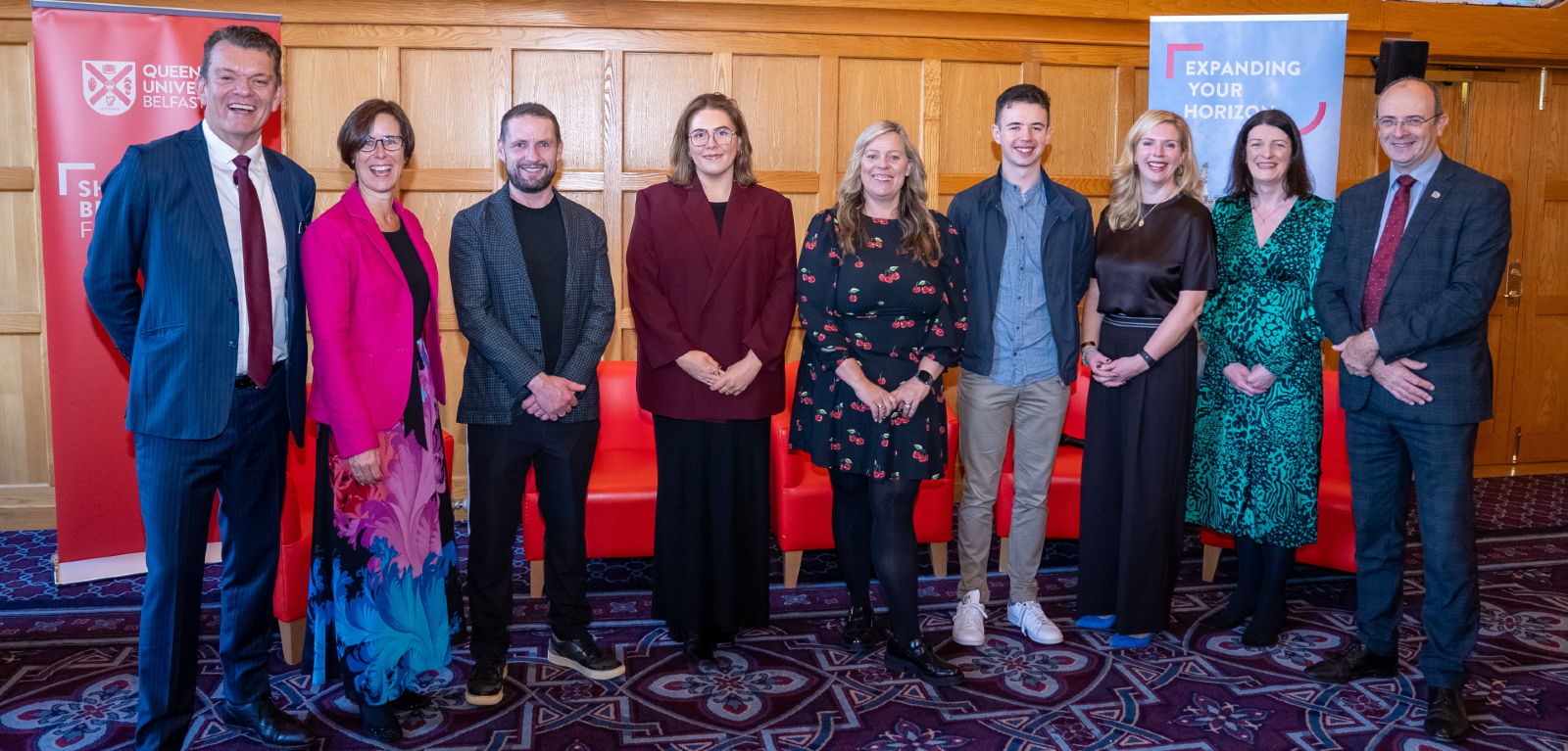 A group of people, including author Katriona O'Sullivan, stand posed in a university grand hall, looking towards the camera.
