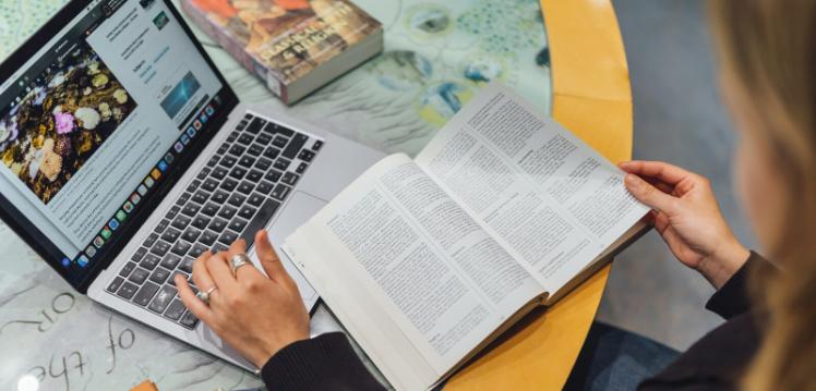 Laptop and open book on top of desk in CS Lewis reading room