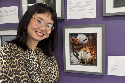 Student Lu Li stands in front of her photo submission for the AEL photography competition
