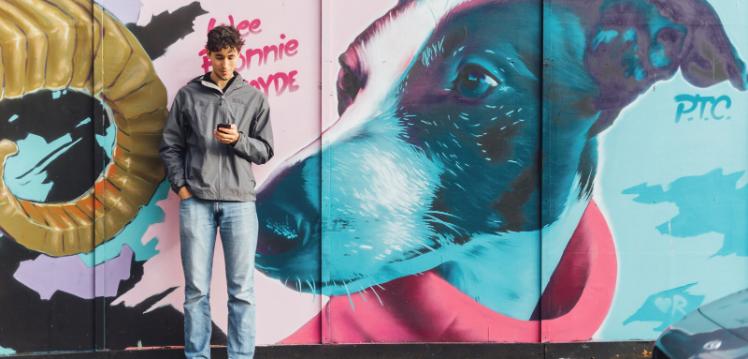 Student Lucas standing in front of graffiti art in Belfast