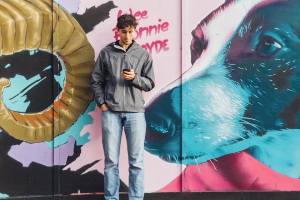 Student Lucas stands against graffiti wall in Belfast