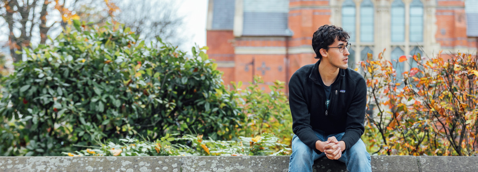 Student Lucas sitting on wall in front of Lanyon