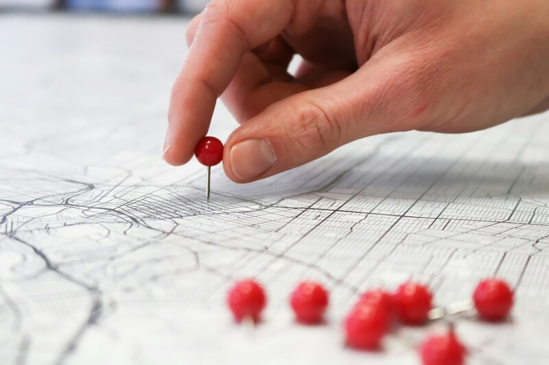 Person placing red pins on map